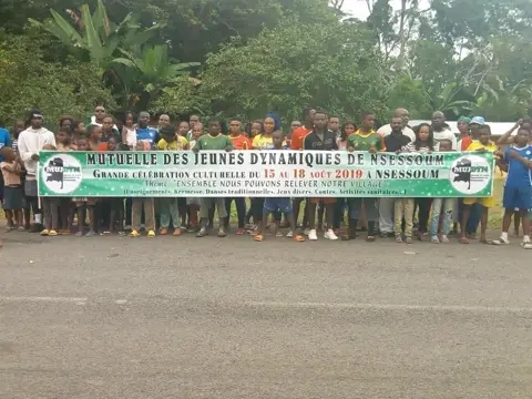 Le village rassemblé derrière la banderole de MUJDYN, au bord de la route.
