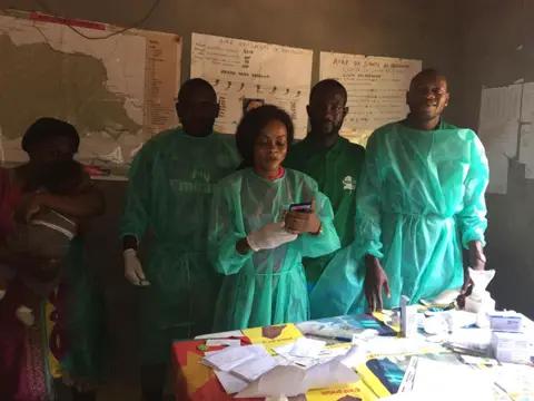L’équipe de santé en blouses vertes pose derrière la table des médicaments.