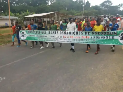 La banderole de MUJDYN ouvre la marche sur la route du village.