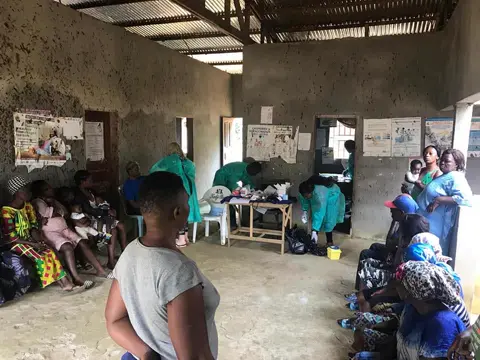 Des mères et leurs enfants attendent leur tour dans la grande salle du centre de santé.